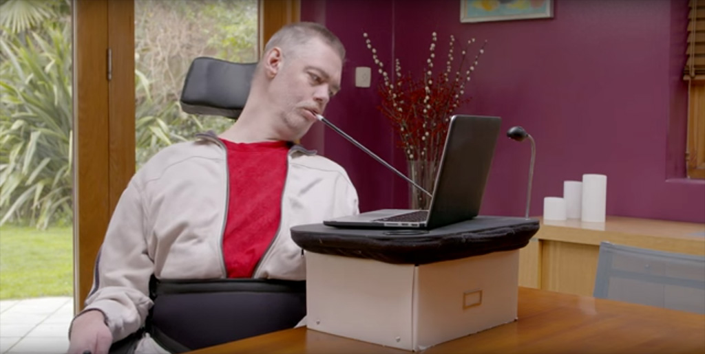 person using a mouth wand to operate a computer keyboard